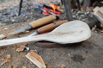 Freshly carved spoon and tools by the campfire
